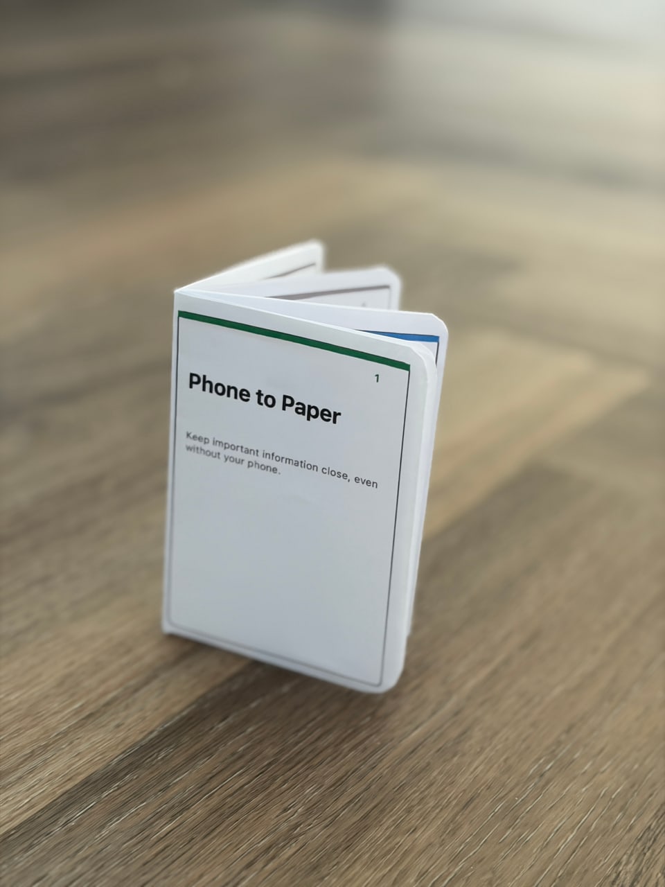 A folded Phone to Paper booklet standing on a wooden table